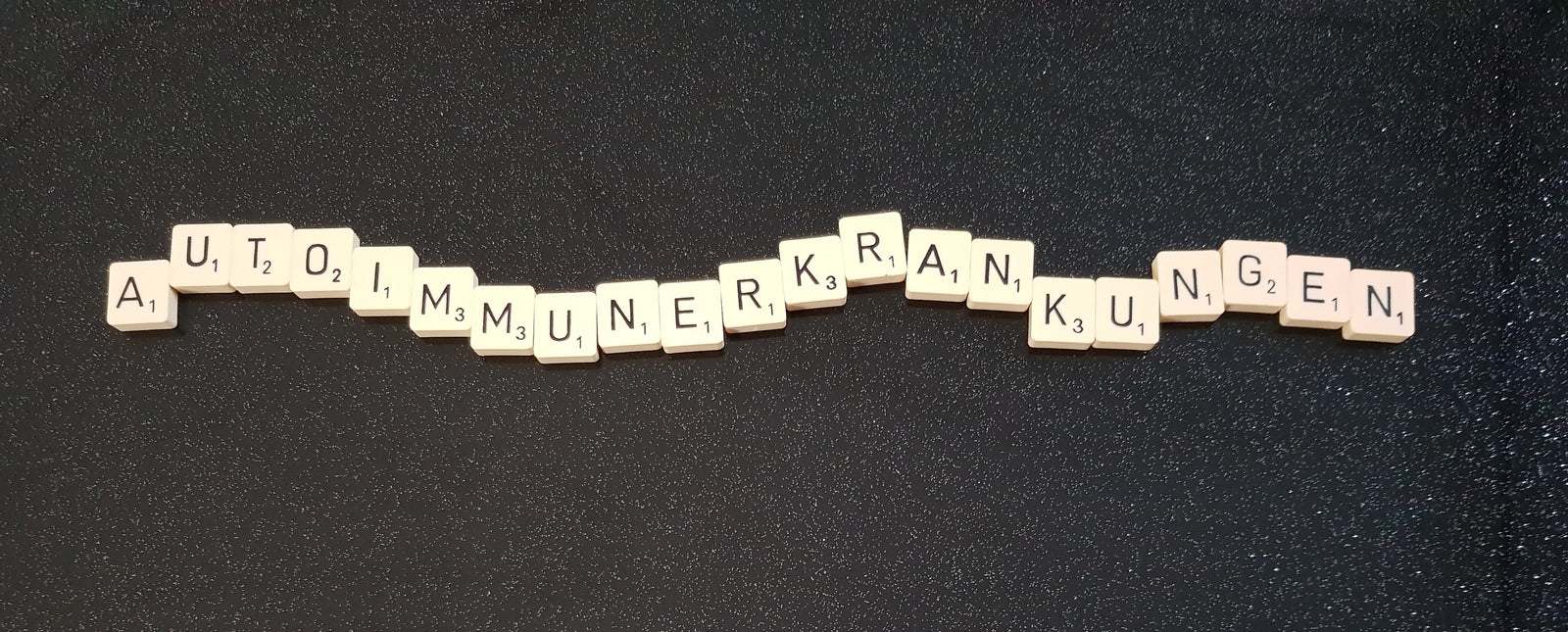 Das Wort Autoimmunerkrankungen mit Bausteinen ausgelegt auf schwarzem Hintergrund