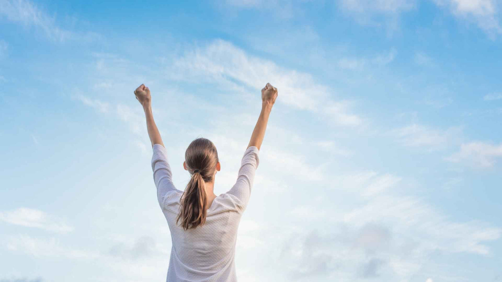 Frau von hinten, die ihre Fäuste hoch in die Luft streckt