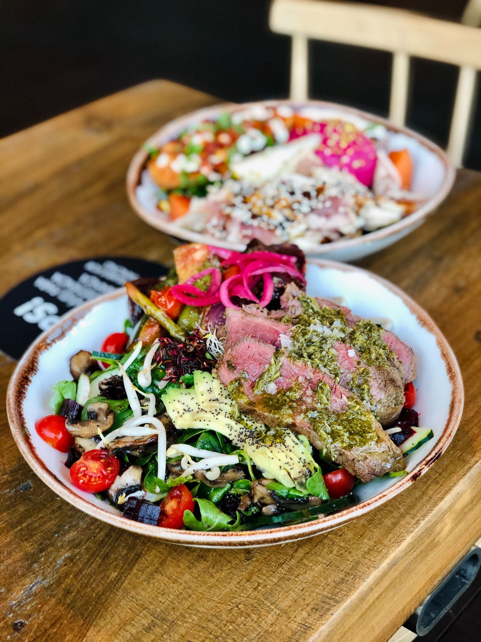 Ein Salat mit Lachs, Avocado, Tomaten und Sprossen nach der Paleo Ernährungsweise steht auf dem Tisch.