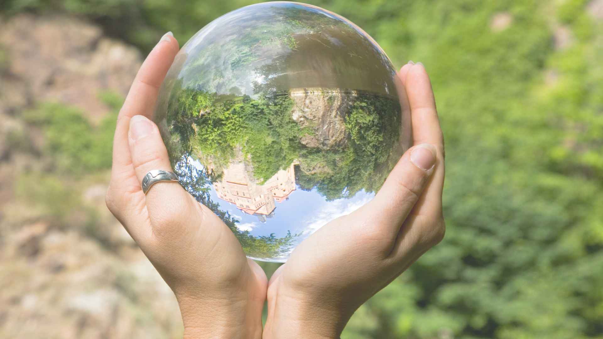 Glaskugel in den Händen einer Frau, die ein Haus auf dem Kopf stehend zeigt