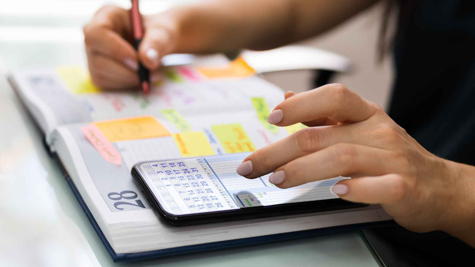 Frauenhände, die mit einem Kalender und einem Smartphone arbeiten