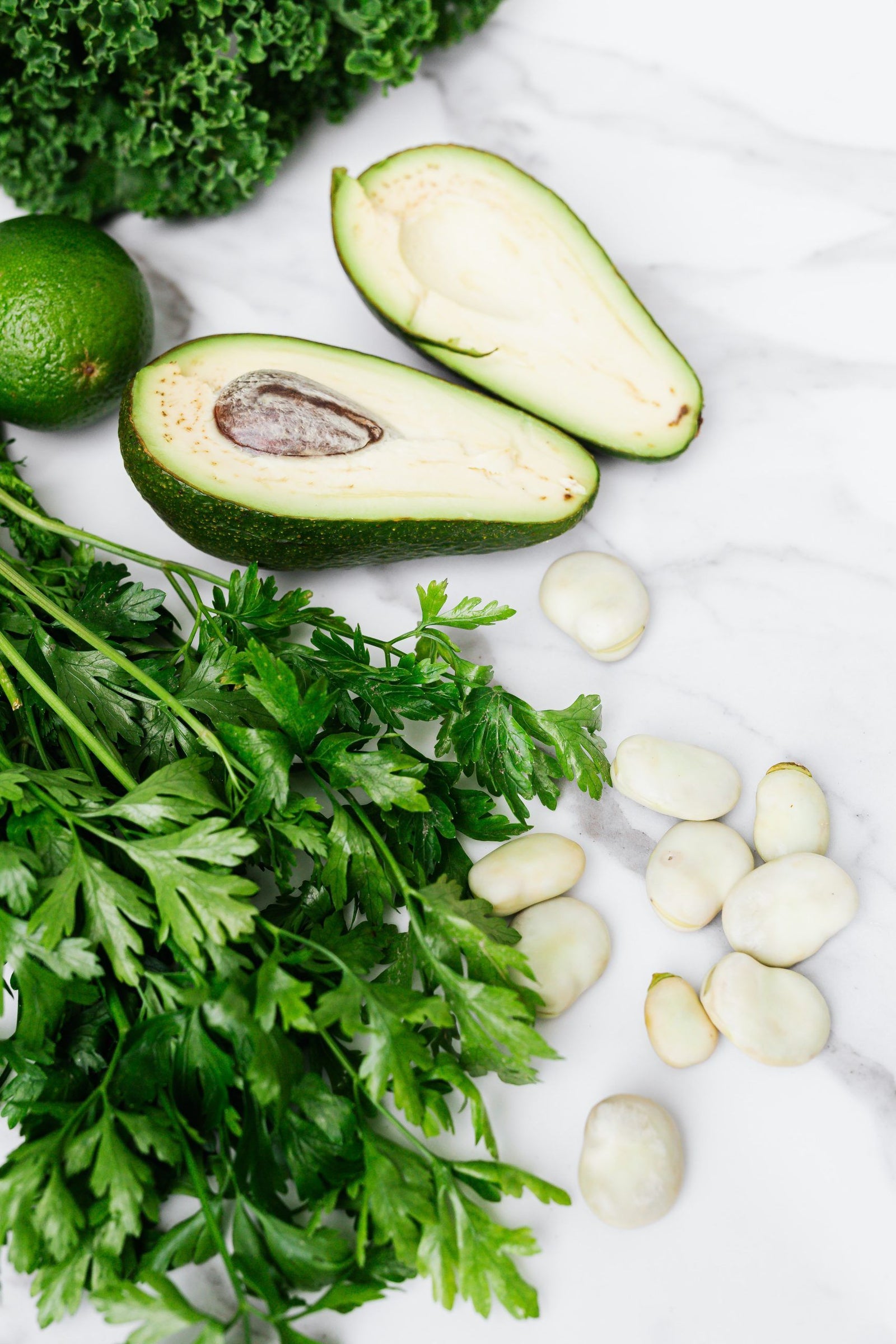 Gesunde Ernährung im Alltag funktioniert mit Gemüse und Obst, wie Avocado, Sellerie, Knoblauch, Limette und Salat.