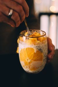 Chia-Samen mit Orangen sind aufbereitet in einem Glas Joghurt.