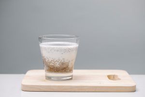 Ein Glas Chia-Samen Pudding steht auf einem hellen Holzbrett.