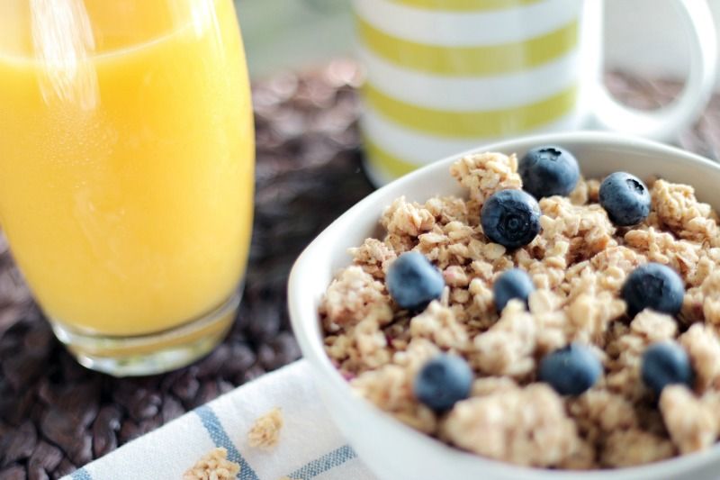 Müsli und mit Blaubeeren und Orangensaft in einem Glas daneben sind ein Frühstück mit viel Zucker, von dem man eine Diät machen sollte.