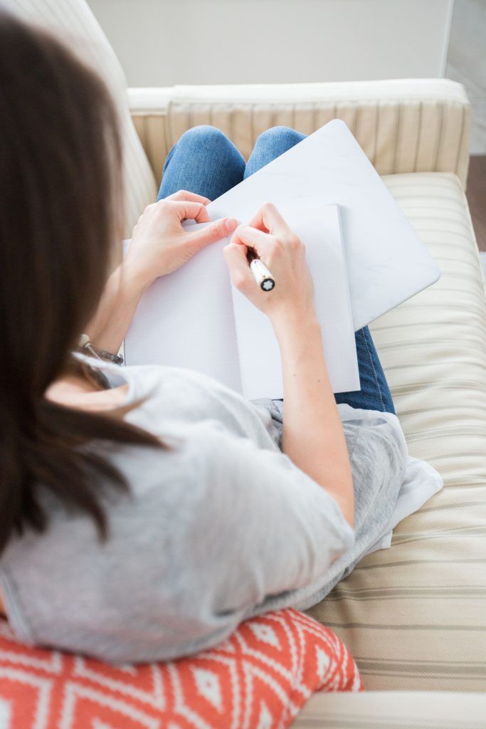 Fehler beim Abnehmen: Eine Frau sitzt auf ihrer Couch und macht sich Notizen zum Thema.