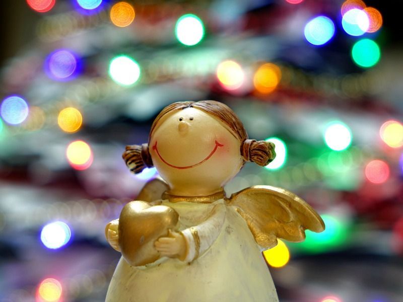 Der Engel hält vor dem dekorierten Weihnachtsbaum ein Herz und wünscht allen eine gute Ernährung an Weihnachten.
