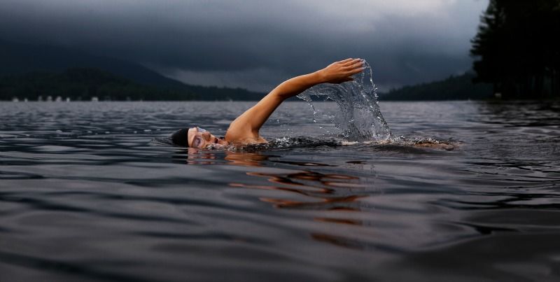 Für diese Frau, die in einem See bei dunklen Wolken am Himmel kraulen geht, ist Sporternährung ein wichtiges Thema.