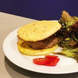 Low Carb Burger auf einem Teller mit Salat und Tomatenscheiben
