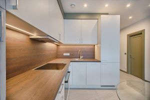 Eine saubere, offene Küche mit weißen Schränken und aufgeräumter Holzfläche ist Teil einer gesunden Raumgestaltung.