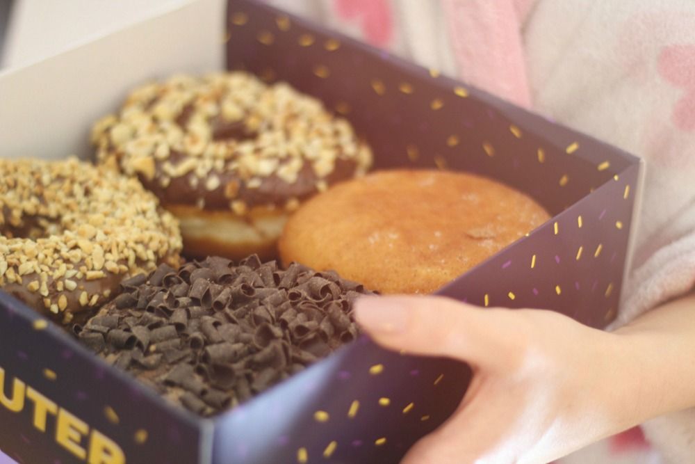 Fehler beim Abnehmen: Eine Box mit Schokoladendonuts liegen in der Hand einer hand.