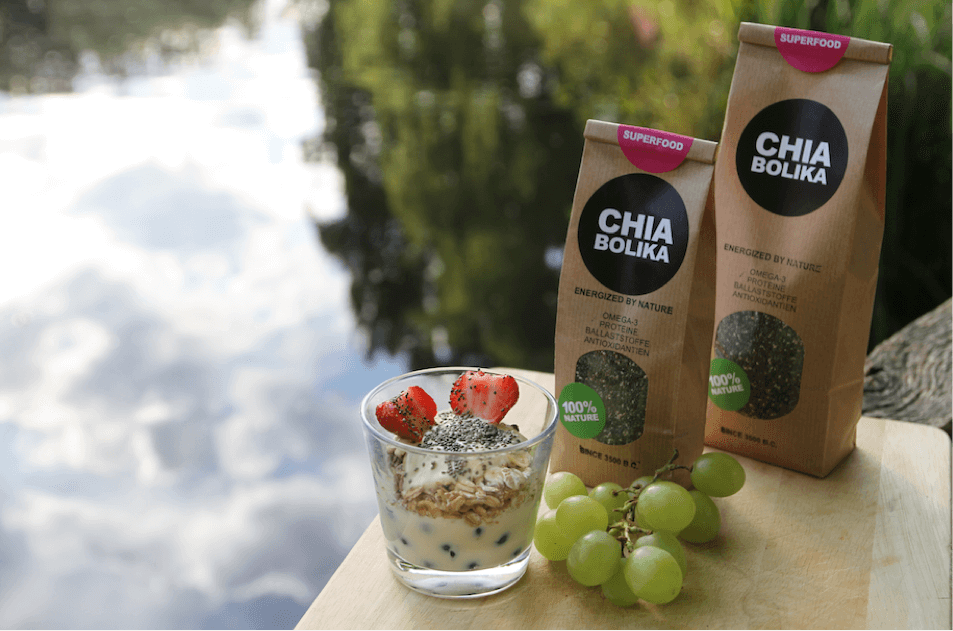 Chia Samen in Joghurt mit Blaubeeren, Nüssen und Erdbeeren am See mit Trauben und Chia Samen Packung von Chiabolika angerichtet