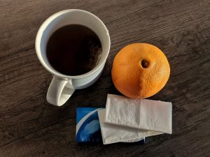 Tasse Tee, Obst und Taschentücher auf einem Tisch weil jemand mehrmals hintereinander Grippe bekommt