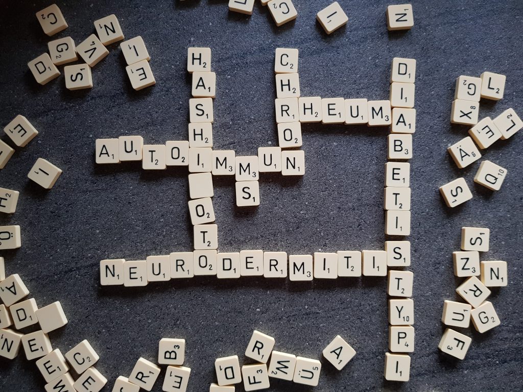 Scrabble Spiel vor schwarzem Hintergrund mit den gelegten Wörtern Neurodermitis, Diabetis, Autoimmun und weitere
