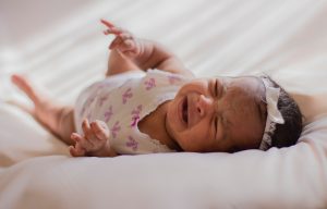 Schreiendew Baby liegt auf dem Bett weil es unter Verdauungsproblemen leidet