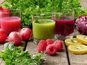 Gesunder roter und grüner Smoothie im Glas mit Früchten drumherum um den Körper zu entgiften