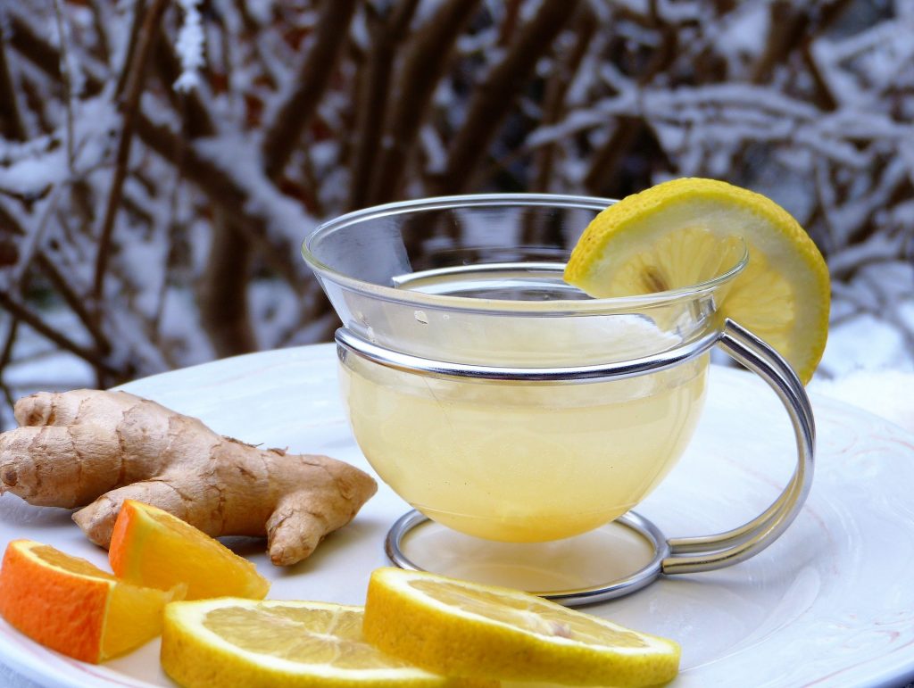 Heisse Zitrone im Glas mit Orangenscheiben, Ingwer und Zitronenscheiben daneben zur Stärkung des Immunsystems