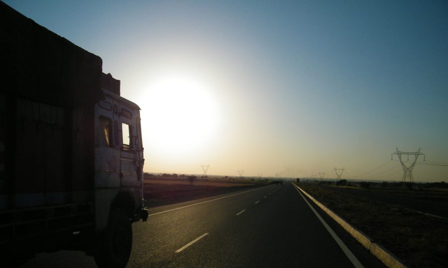 LKW fährt auf Strasse Richtung Sonne
