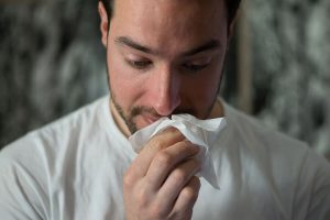 Mann niest in Taschentuch weil er unter Heuschnupfen leidet