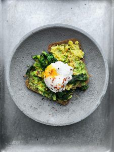 Fehler beim Abnehmen: Avocadobrot mit Ei, das auf einem grauen Teller liegt, gehört zu einer guten Sporternährung.