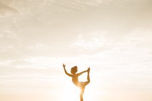 Eine Frau macht Ballett vor dem strahlenden Sonnenlicht und schützt sich mit natürlicher Sonnencreme.