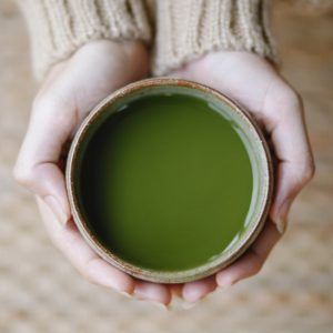 Matcha-Tee, in einer Matchaschale von zwei Händen gehalten wird, hat eine gesunde Wirkung.