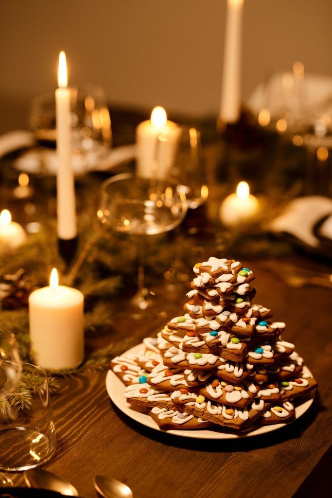 Weihnachtskekse stehen auf einem gedeckten Tisch mit Kerzen und führen zu Weihnachtskilo-Frust und dazu, dass jemand die Weihnachtspfunde später wieder verlieren muss.