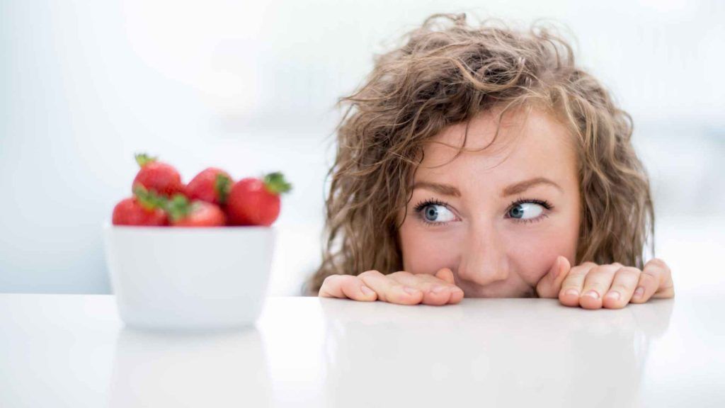 Frau die hungrig eine Schale Erdbeeren betrachtet