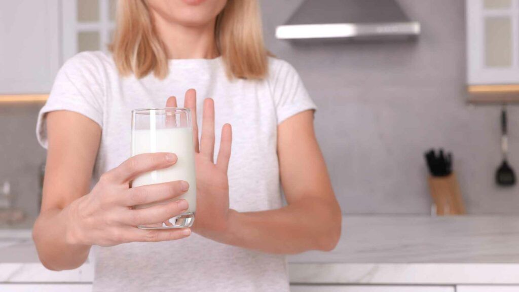 Frau, die ein Glas Milch abwehrend vor sich hält